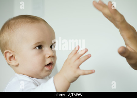 Baby reaching for mother's hand Stock Photo