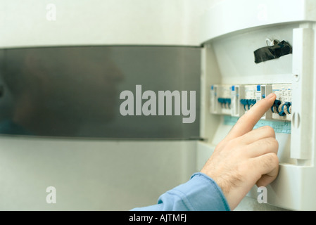 Man switching fuse in fuse box, close-up of hand Stock Photo