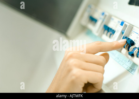 Woman switching fuse in fuse box, close-up of hand Stock Photo