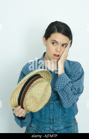Teenage girl holding cheek, open mouth, looking away Stock Photo