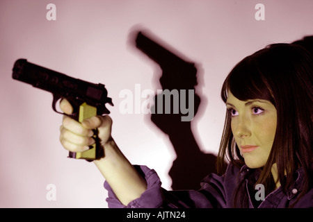 young woman with brown hair holding a handgun Stock Photo