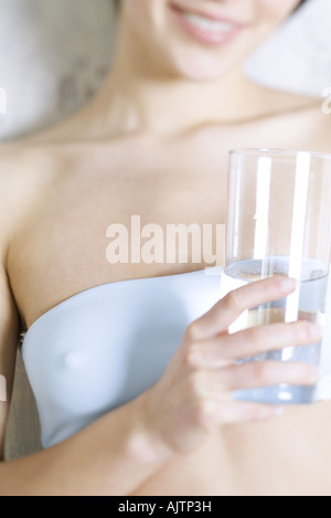 Cropped view of woman holding glass of water, dressed in tubetop Stock Photo