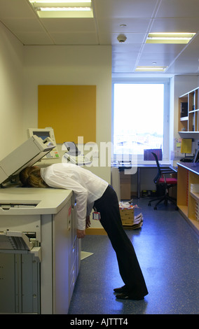 Office life and Interiors Part Two. Woman asleep on a photocopier. Stock Photo
