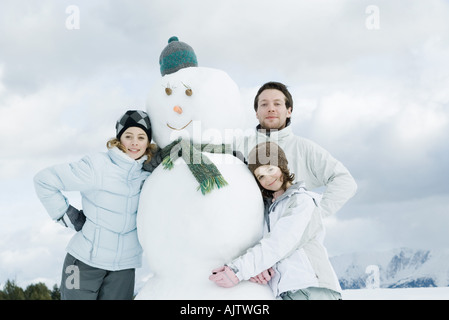 Young friends posing next to snowman, portrait Stock Photo