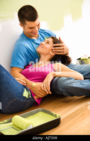 Couple sitting on floor embracing taking break from interior painting Stock Photo
