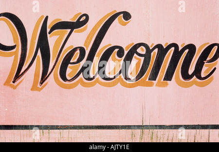 Close up of a fading handpainted sign in cursive script stating Welcome Stock Photo