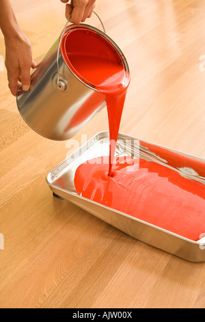 Caucasian woman pouring red paint from can into tray Stock Photo