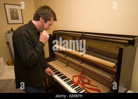 Piano tuner at work tuning an old German upright piano Stock Photo