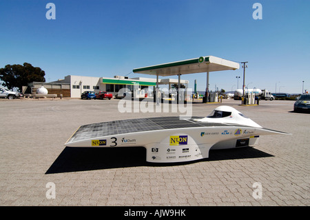 A solar racing car, powered only by sunshine, standing in front of a traditional petrol station. Stock Photo