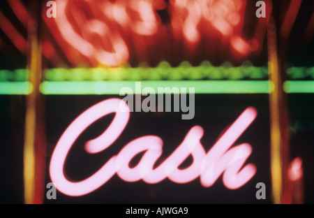 Red neon sign with cursive script announcing Cash and with reflection and green light above Stock Photo