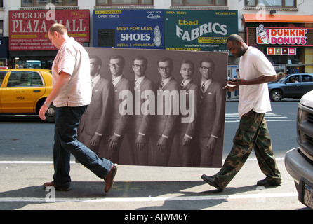 Two men carrying a piece of art on 8th Ave NYC Stock Photo