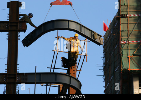 Construction workers put steel girders into place high up on a new skyscraper in central Beijing. Stock Photo
