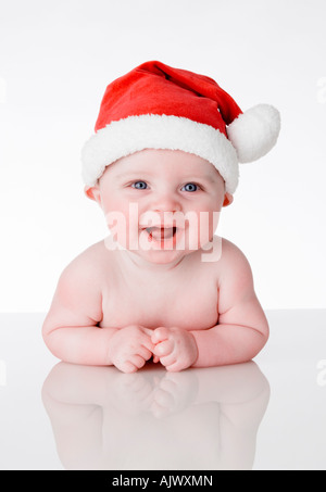 portrait format picture of a cute beautiful laughing baby wearing a Santa Father Christmas hat on a white perspex background Stock Photo