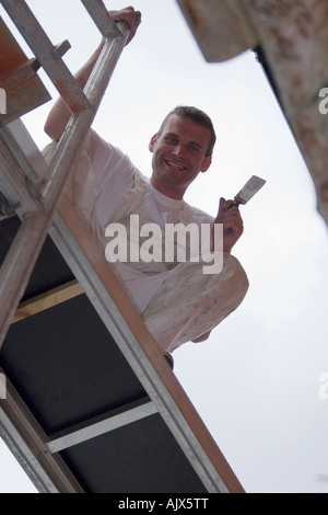 portrait of young painter decorator standing on scaffold boards holding paint brush in hand Stock Photo