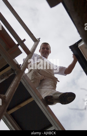 portrait of painter decorator standing on scaffold boards on top of house Stock Photo