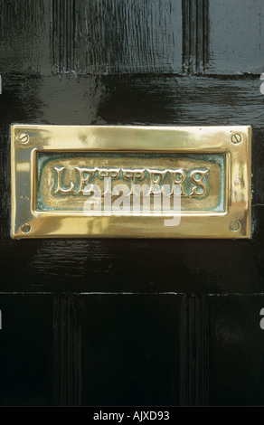 Polished brass letterbox in black front door Stock Photo