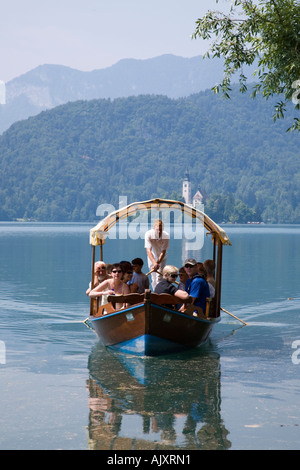 Lake Bled in summer with traditional wooden pletnja rowing boat ferrying tourists. Bled Slovenia Stock Photo