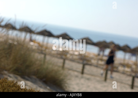 Straw um brellas on the beach and people making jogging exercise on the beach Stock Photo