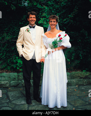 Lifestyle. Man and woman wedding couple. Bride & groom posing outdoors in garden. Stock Photo