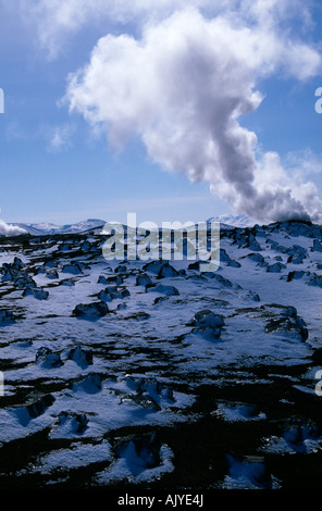 Steam rises from behind the snowy lava rocks near Myvatn Thermal Baths in spring, North East Iceland, Iceland Stock Photo