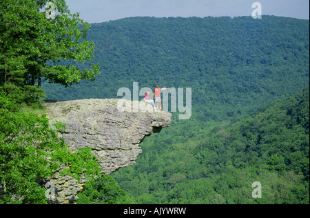 Hikers stand on a granite outcrop above the hardwood forest of the Ozark Mountains overlooking the Buffalo National River Stock Photo