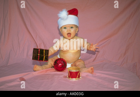 USA ARKANSAS HOT SPRINGS A baby girl wearing a Santa Clause Hat plays with ornaments at Christmas Stock Photo