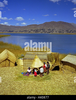 Indigenous family rest & socialize by rural straw hut in stunning natural setting Titicaca Lake Peru South Latin America Stock Photo