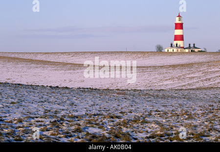 ROUGH GRASSLAND WITH LIGHT COVERING OF SNOW AND LIGHTHOUSE IN BACKGROUND HAPPISBURGH NORFOLK EAST ANGLIA ENGLAND UK Stock Photo