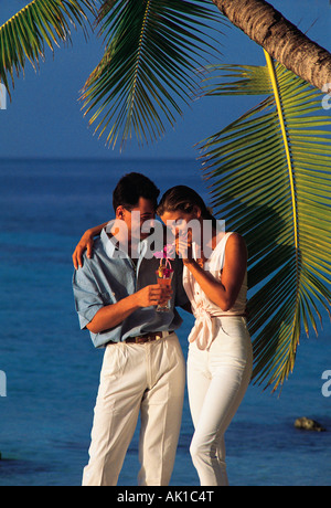 Maldives. Young couple with cocktail standing on tropical beach. Stock Photo