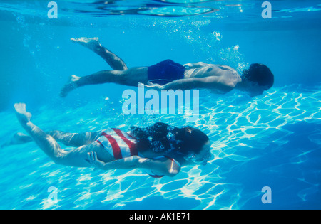 couple swimming underwater in pool Stock Photo