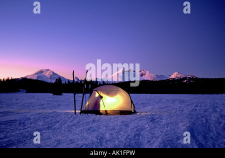 Winter campers and cross country skiers set up a tent in the Cascade Mountains near Mount Bachelor at twilight Stock Photo