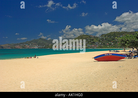 Golden sands of beach with turquoise sea blue sky mountains in background and red boat Stock Photo