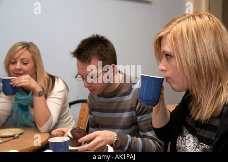 group of three students sitting in a coffee shop enjoying a cup of coffee and some buns Stock Photo