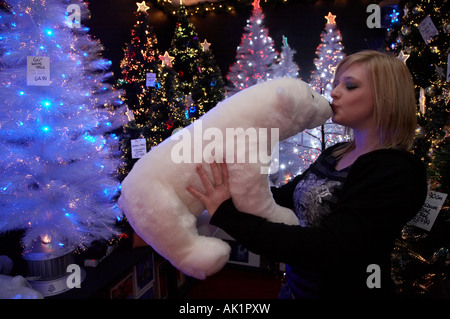 blonde haired female irish student kissing a soft toy polar bear in shop selling christmas trees and decorations Stock Photo