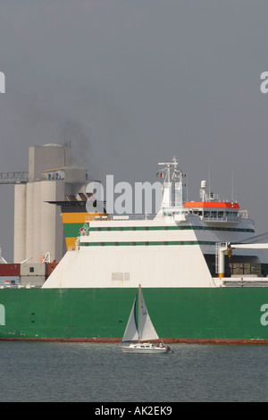 Commercial shipping large container vessel leaves Southhampton docks with small private yacht alongside Stock Photo