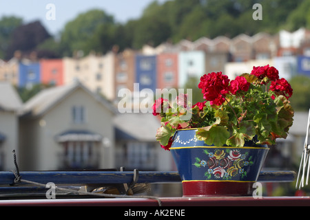Bristol England geranium flowers in painted pot on top of canal long boat roof with the Hotwells district behind Stock Photo
