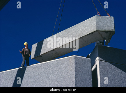 Construction engineer guiding crane positioning prefabricated concrete building section. Stock Photo
