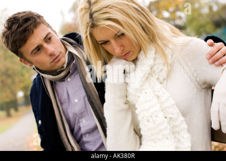 Couple sat on bench in woods consoling Stock Photo