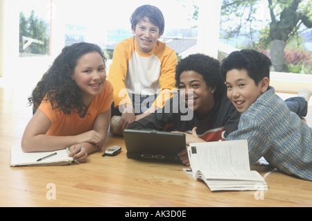 Four teenage kids working on a laptop and school books Stock Photo