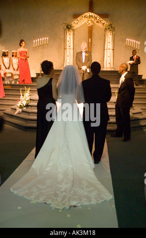 A mixed race bride accompanied her brother and widowed mixed race mother approach the minister at the daughter s marriage to an Stock Photo