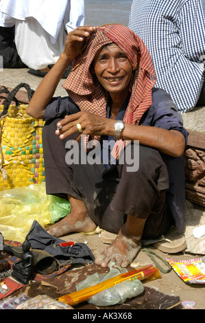 Man selling small souvenirs wearing a kerchief smoking a joint Water Festival Phnom Penh Cambodia Stock Photo