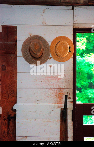 straw hats hanging on wooden cabin wall. Stock Photo