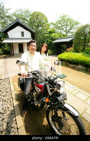 Mature man sitting on motorcycle with woman looking on Stock Photo