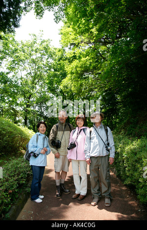 Two mature couples standing in a park, smiling Stock Photo