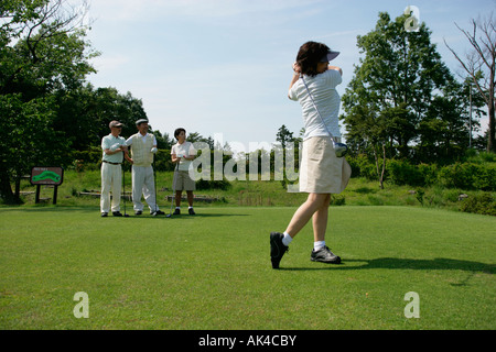Woman playing golf with friends looking on Stock Photo