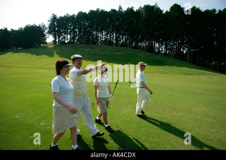 Two couples walking on golf course Stock Photo