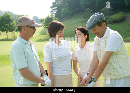 Four mature adults standing at golf course Stock Photo