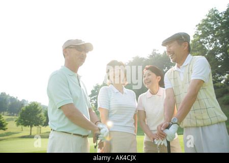 Four mature adults standing at golf course, low angle view Stock Photo