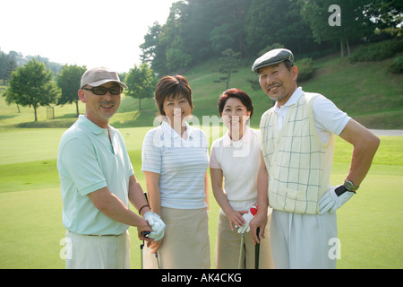 Four mature adults standing at golf course Stock Photo