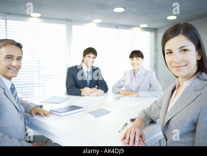 Executives sitting around table, smiling at camera Stock Photo